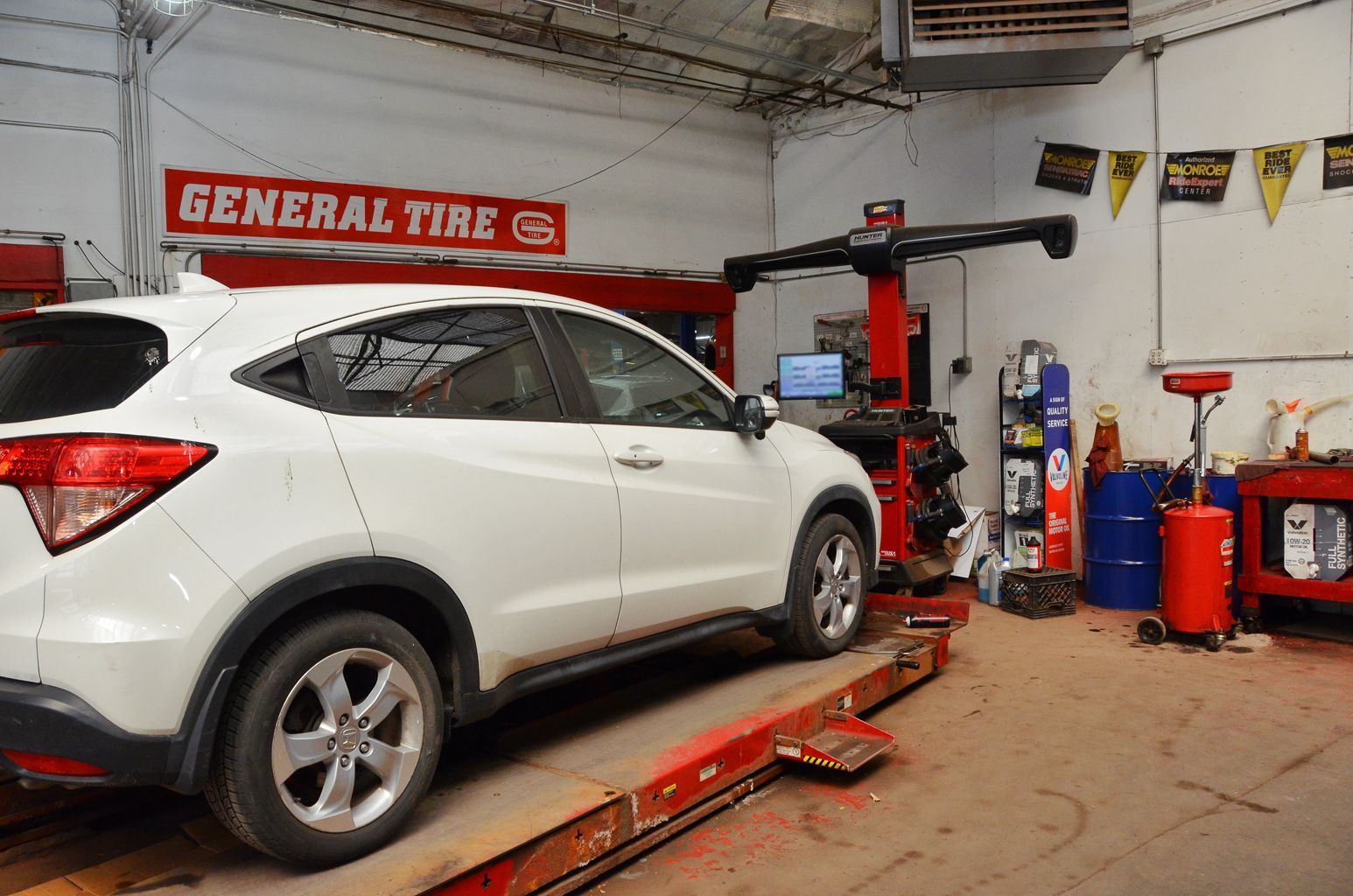 A white car is sitting on a lift in a garage.
