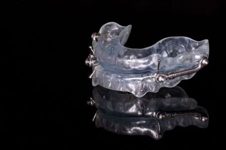 A clear mouth guard is sitting on a black surface.