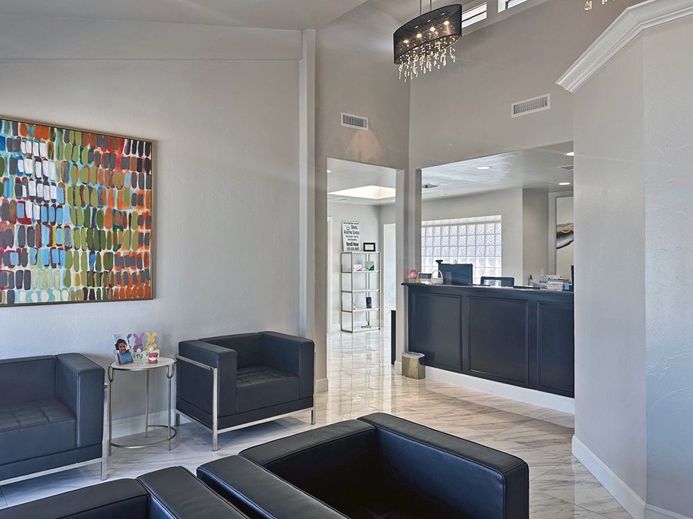 A waiting room with chairs , a table and a painting on the wall.