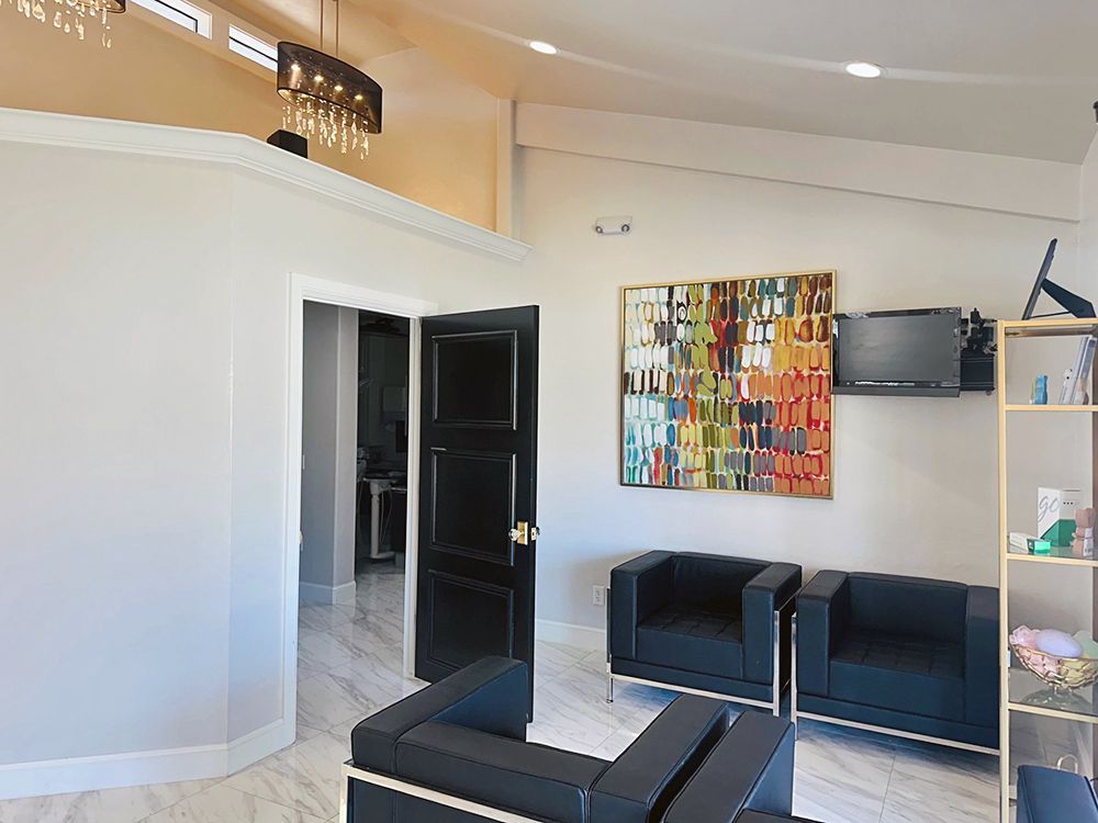 A waiting room with black chairs and a painting on the wall.