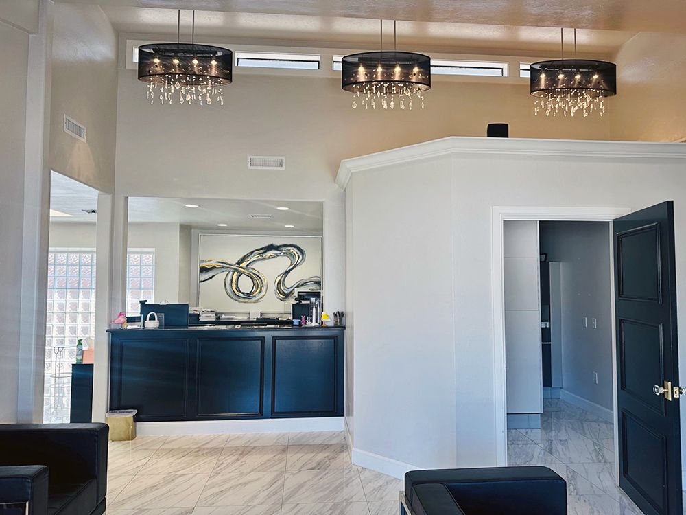 A waiting room with a reception desk , chairs , and chandeliers.