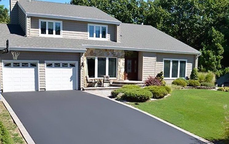 A large house with a lush green lawn and a driveway leading to it