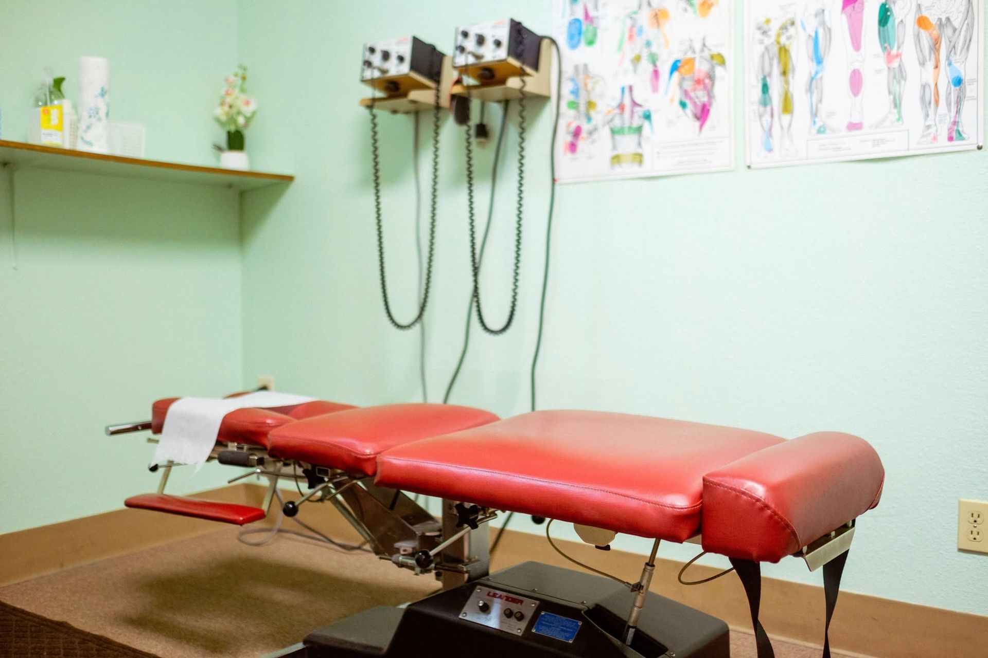 Examination table in a medical exam room with wall-mounted tools and children’s drawings.