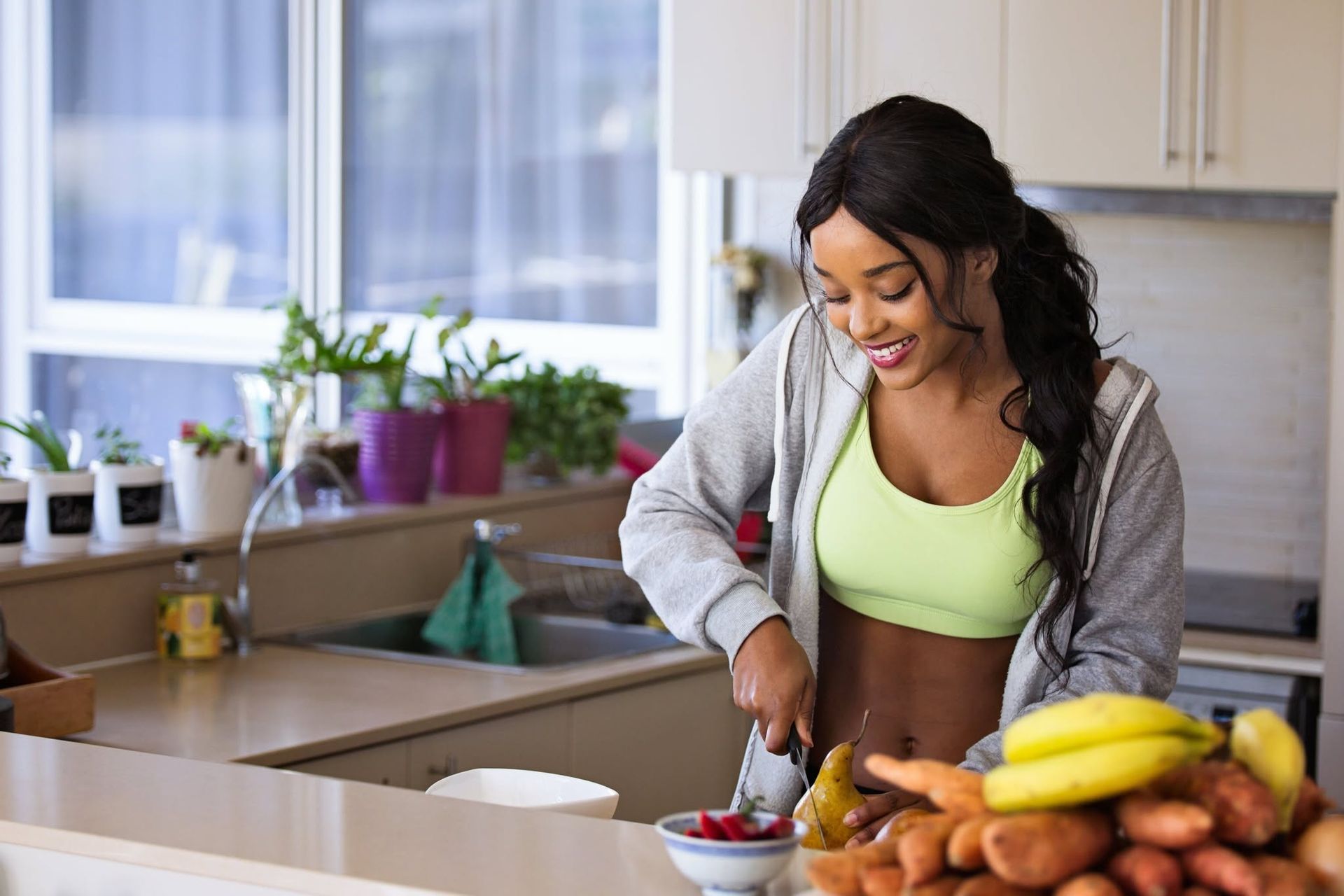 Woman mixing ingredients in a bright kitchen beside bananas and other produce
