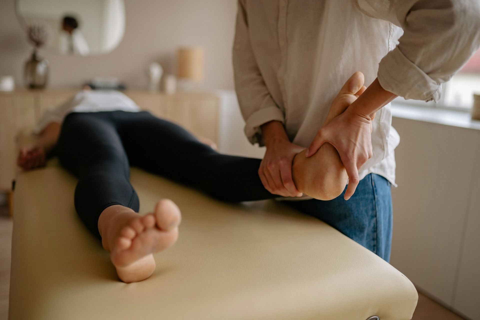 Massage therapist kneading a client’s foot on a treatment table in a spa room