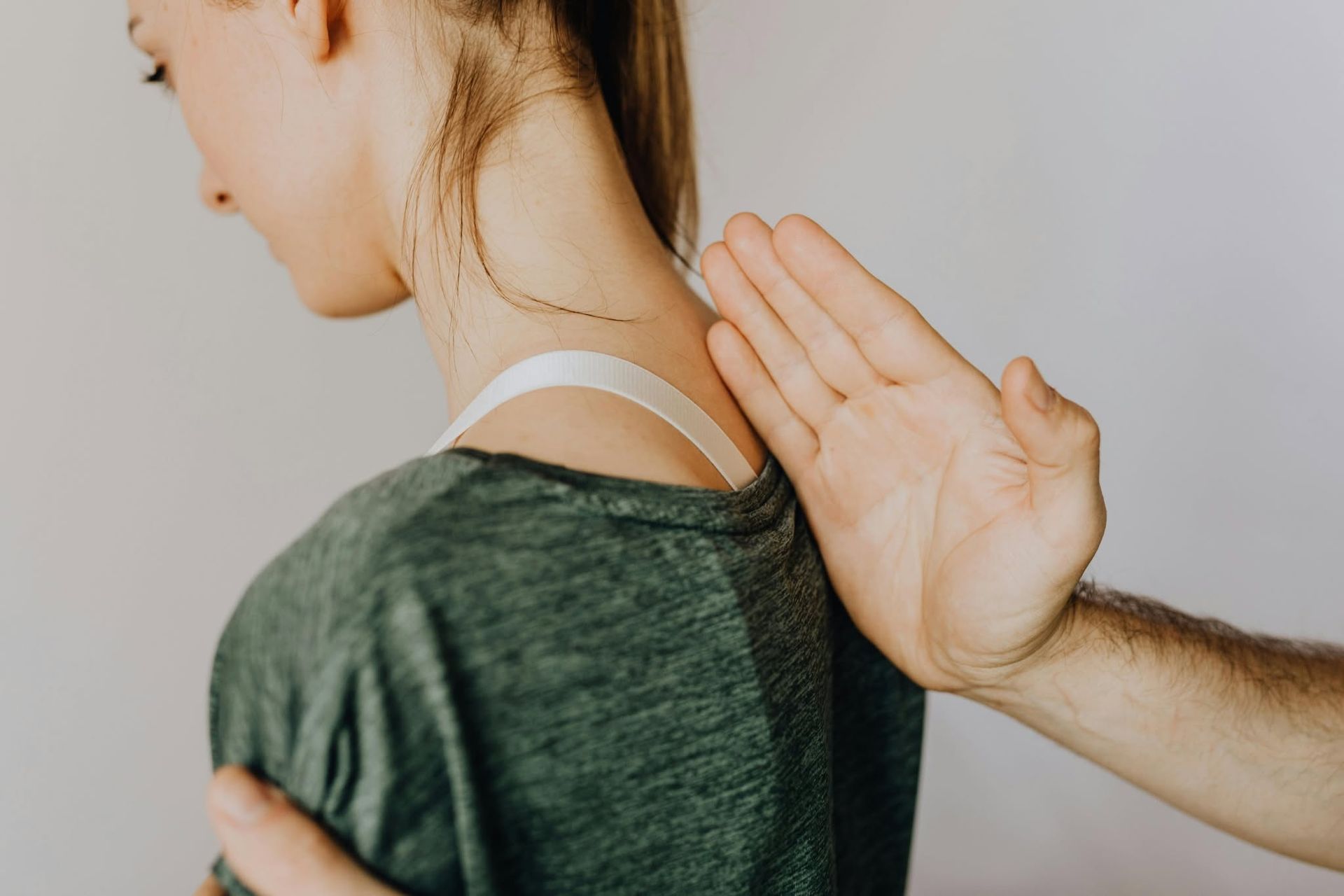 Person with shoulder exposed while another hand presses near the neck and upper back