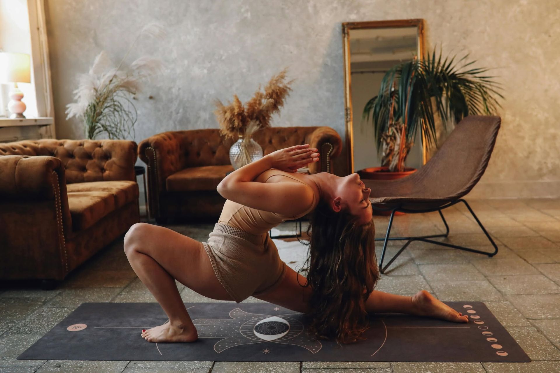 Woman doing a backbend yoga pose on a mat in a cozy living room