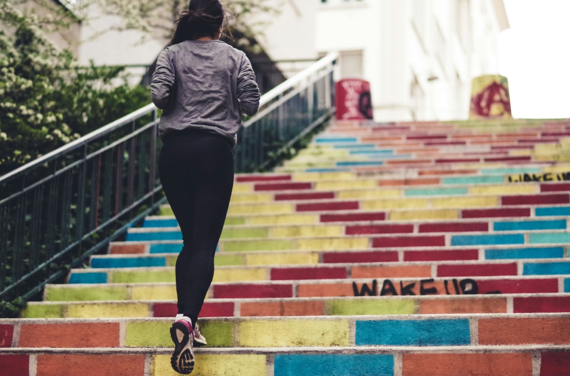 Person running up colorful rainbow-painted stairs outdoors