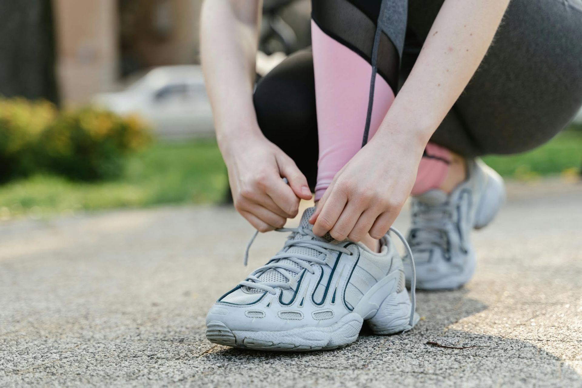 Runner tying shoelaces on a sneaker outdoors on a paved path