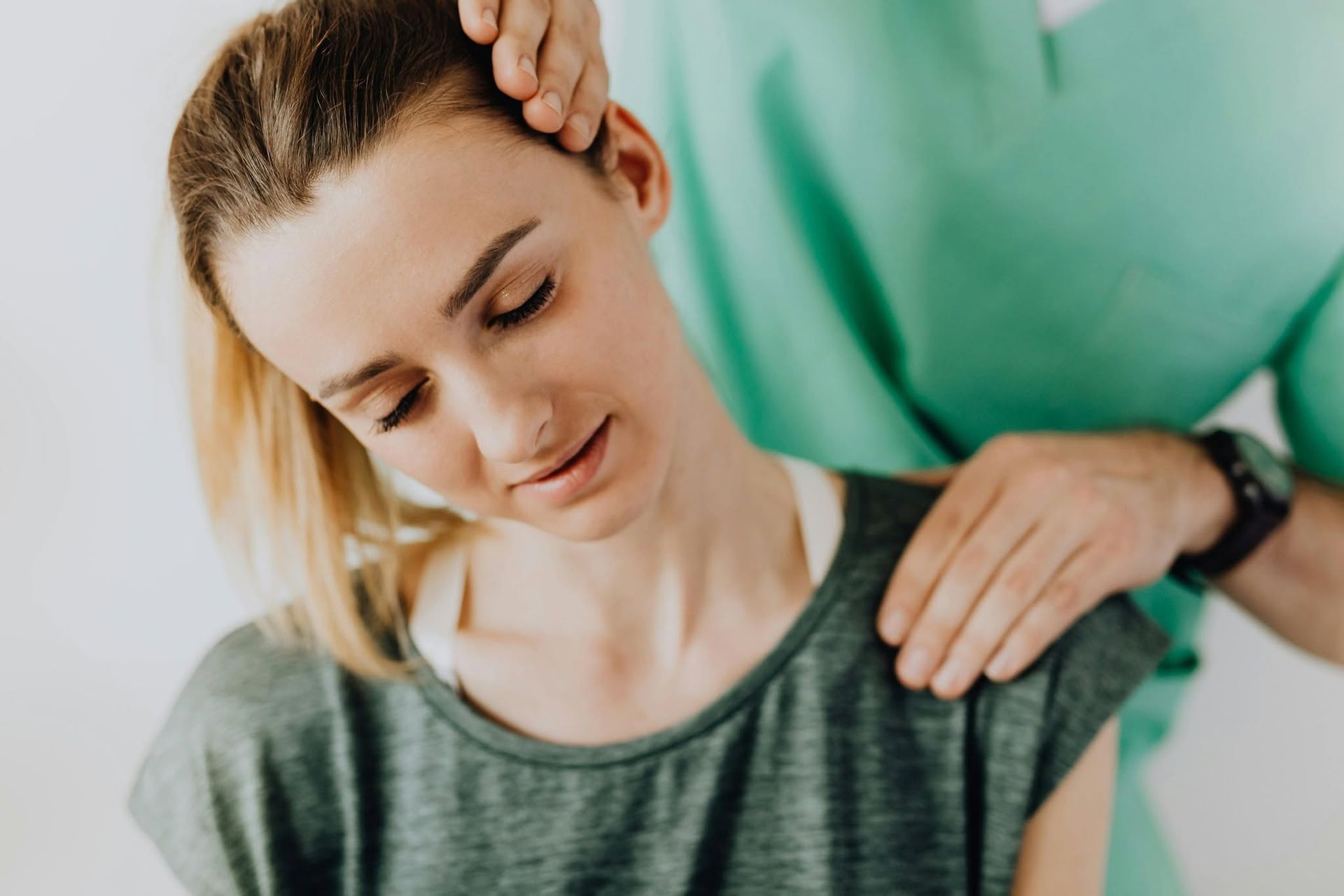 Woman receiving a neck and shoulder massage from a therapist in a green shirt