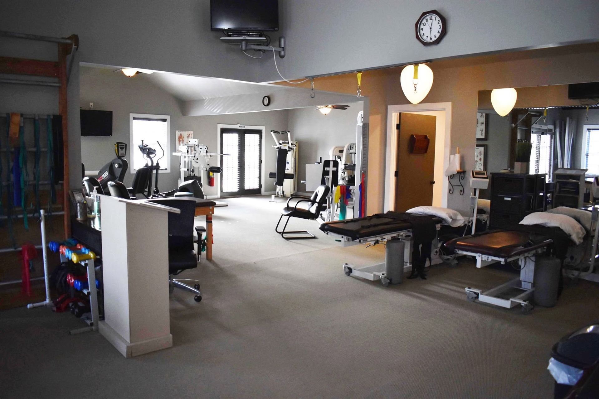 Gym interior with exercise machines, benches, mirrors, and wall clock