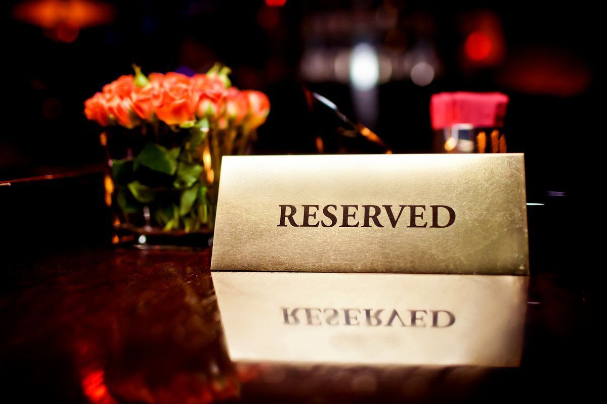 A sign that says 'reserved' is placed on a table next to some flowers.