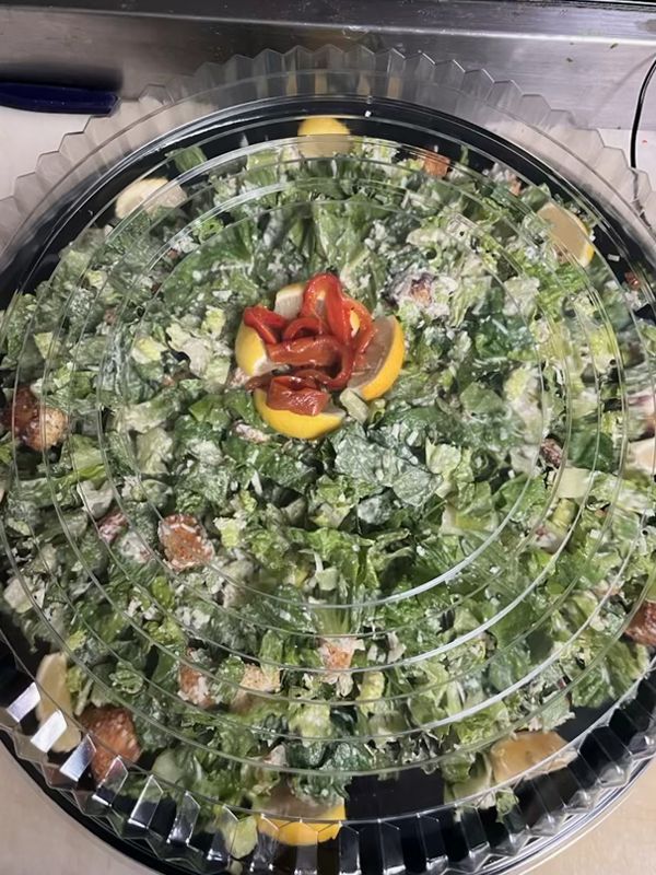 A large salad in a plastic container on a table