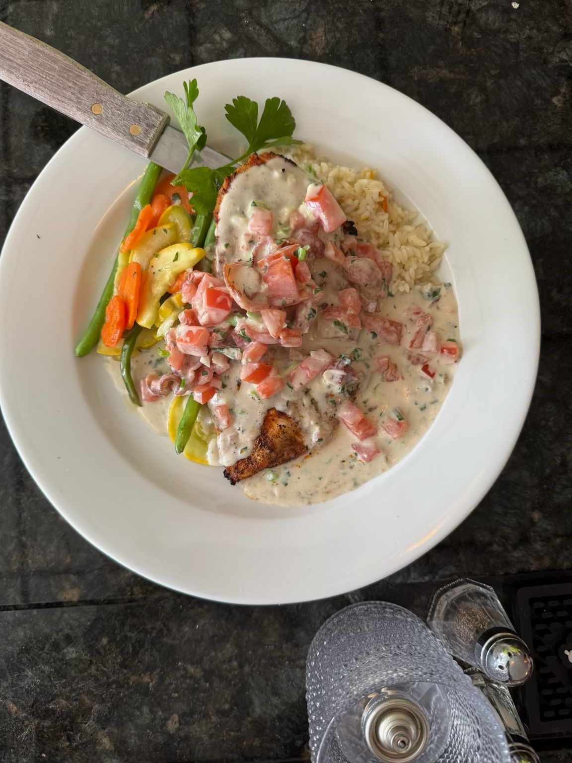 A white plate topped with a piece of meat and vegetables