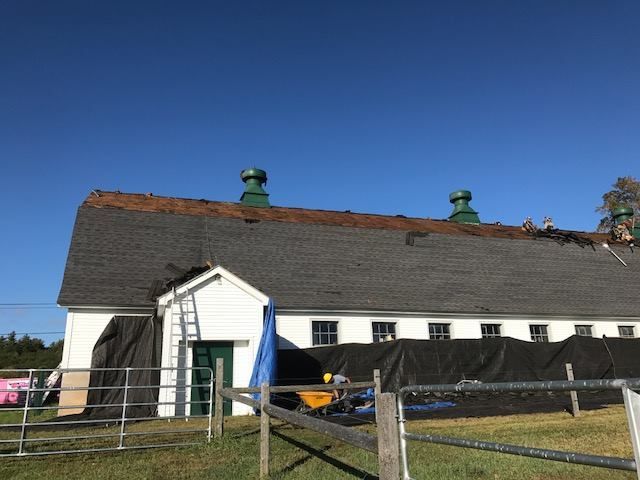A large white building with a roof that is being painted.
