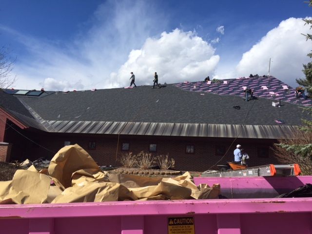 A pink dumpster is sitting in front of a house under construction