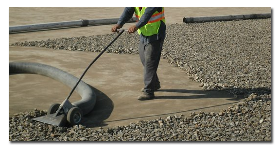 A construction worker is sweeping gravel with a broom