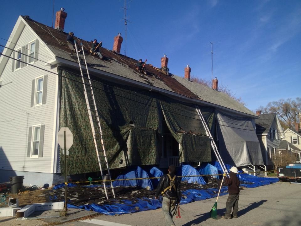 A group of people are working on the roof of a house