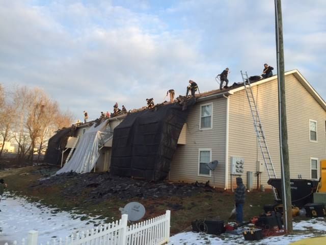 A group of people are working on the roof of a house.