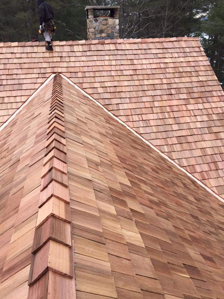 A man is standing on top of a wooden roof.