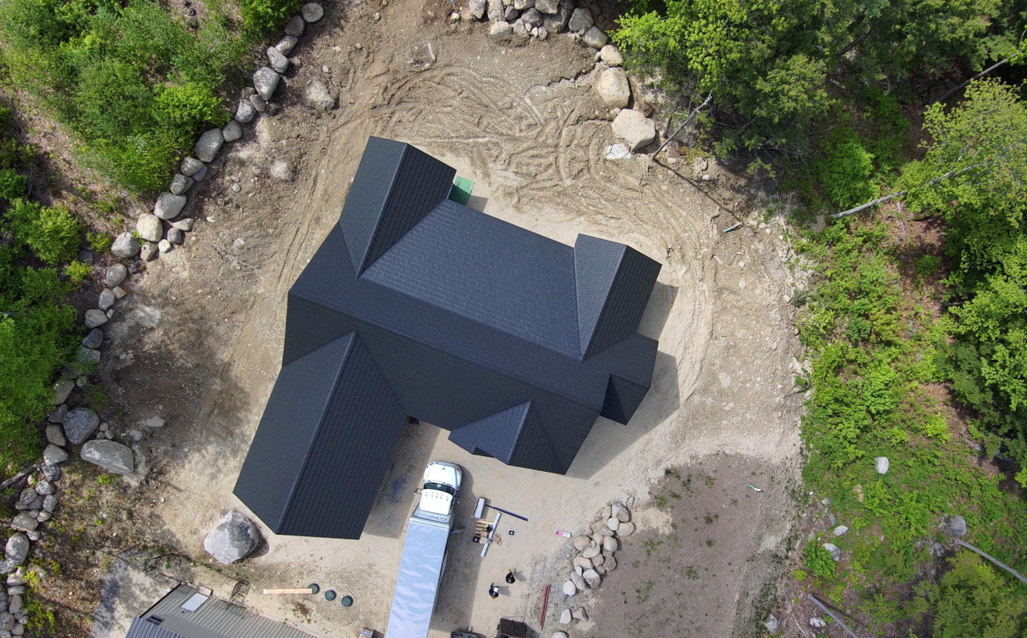 An aerial view of a house under construction in the middle of a forest.
