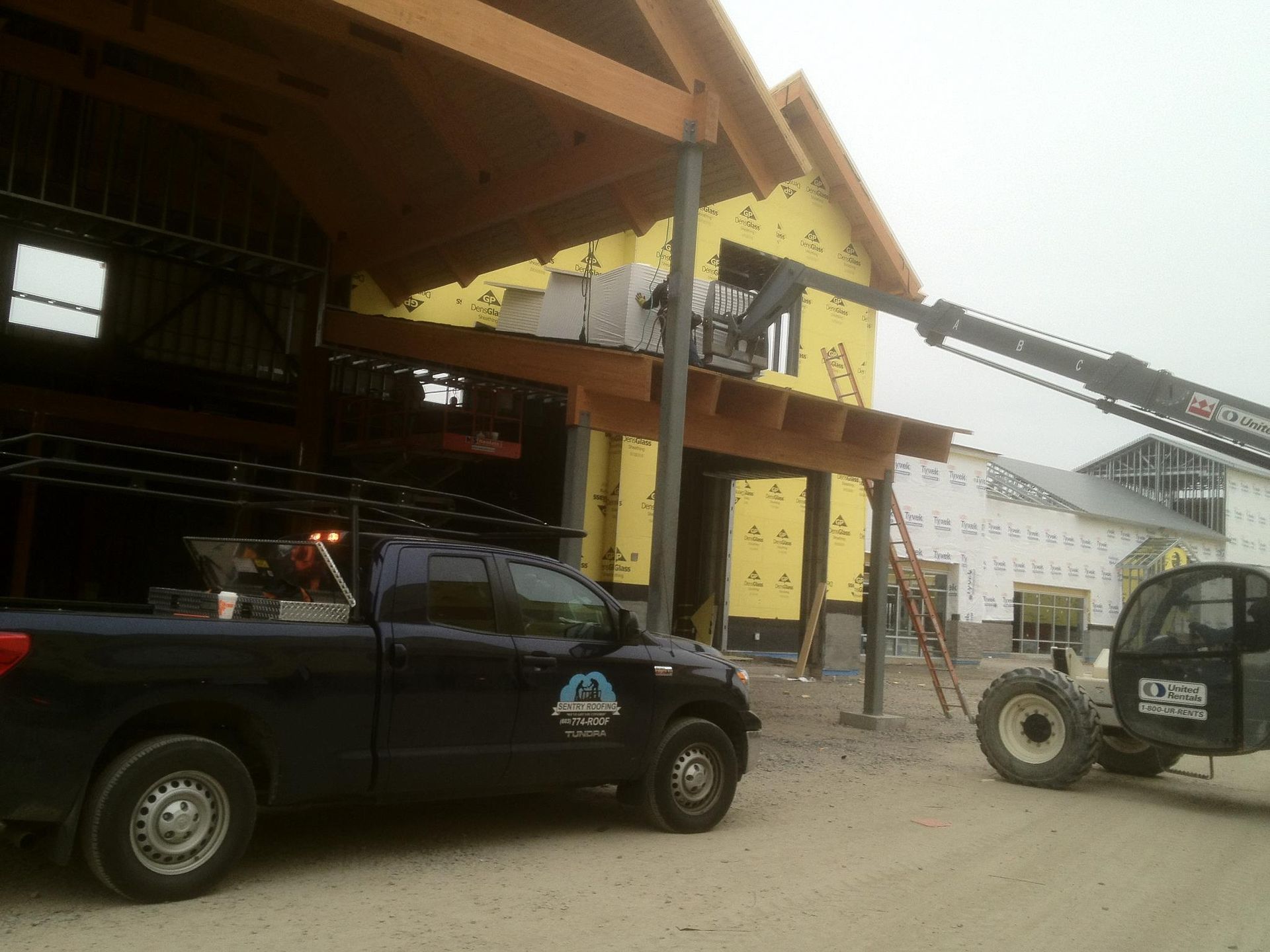 A blue truck with the word aa on the side is parked in front of a building under construction