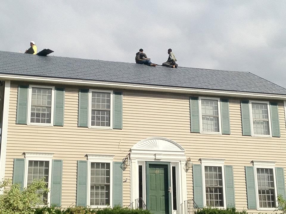 Two men are sitting on the roof of a house