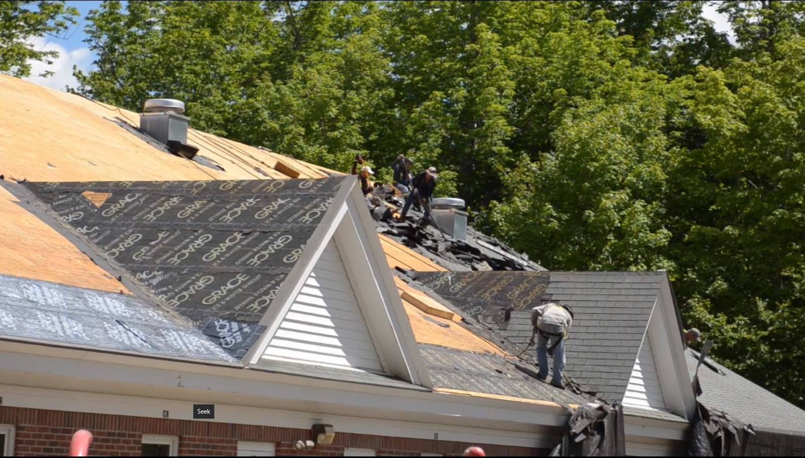 A group of people are working on the roof of a house.