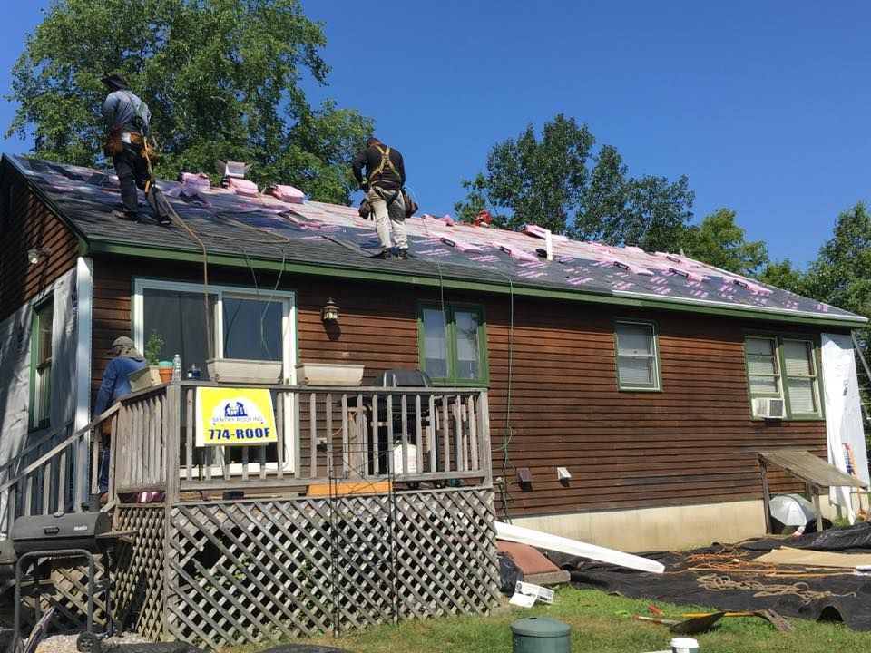 A group of men are working on the roof of a house.