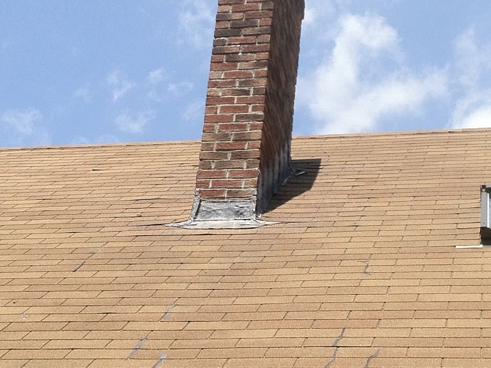 A brick chimney is sitting on top of a roof