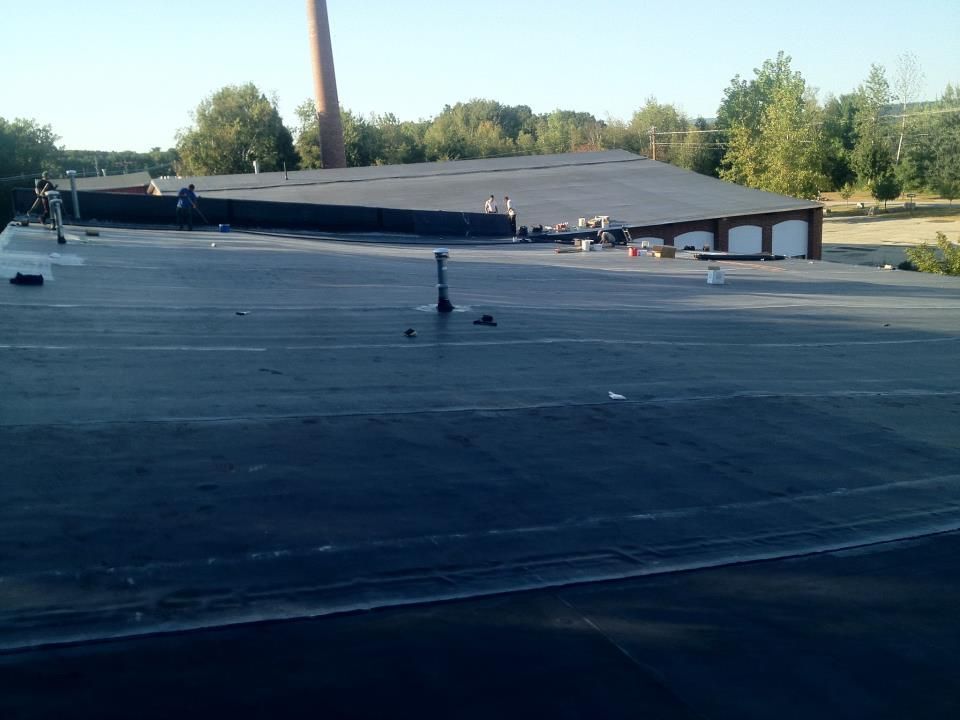 The roof of a building with a chimney in the background.