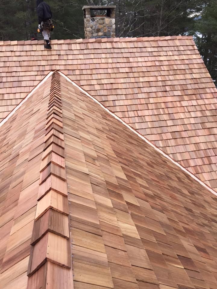 A man is standing on top of a wooden roof.