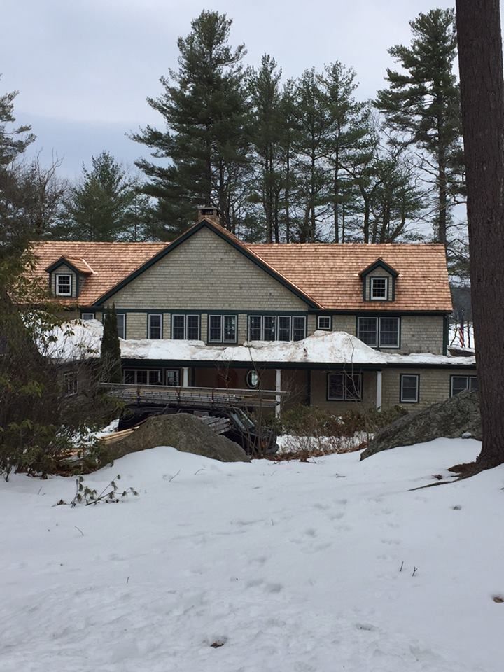 A large house is surrounded by snow and trees