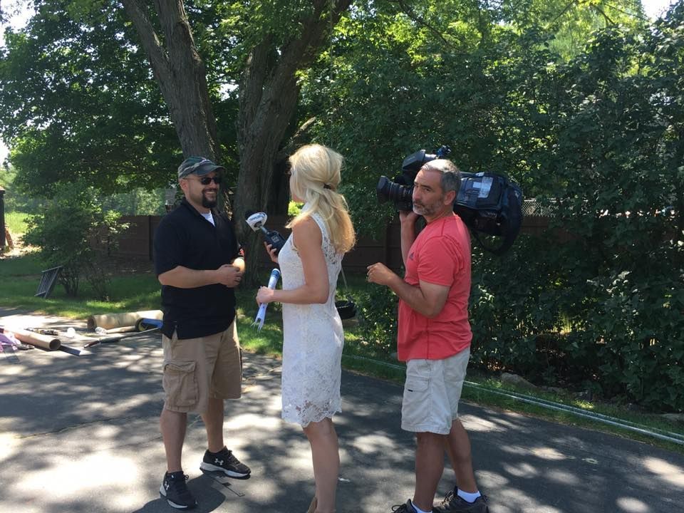 A woman in a white dress is being interviewed by two men
