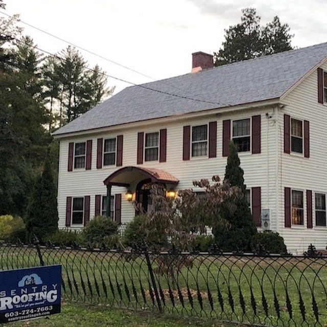 A large white house with red shutters and a sign that says senior roofing