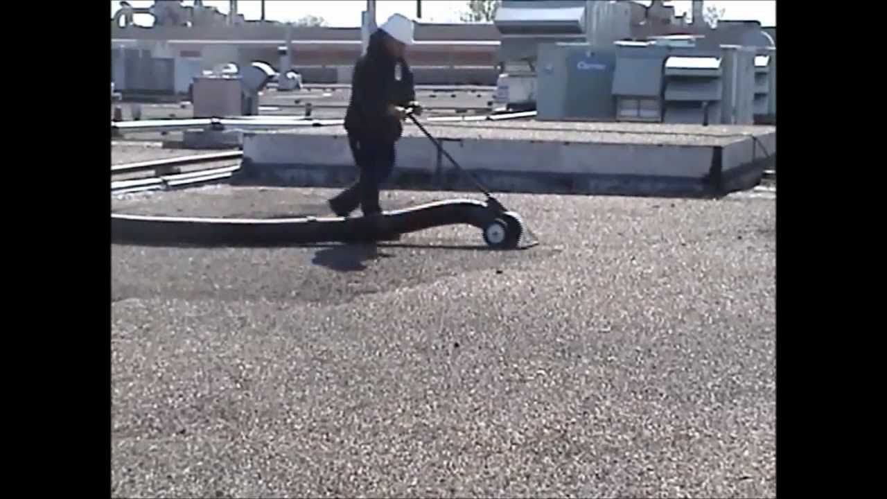 A man is pushing a scooter on a concrete surface.