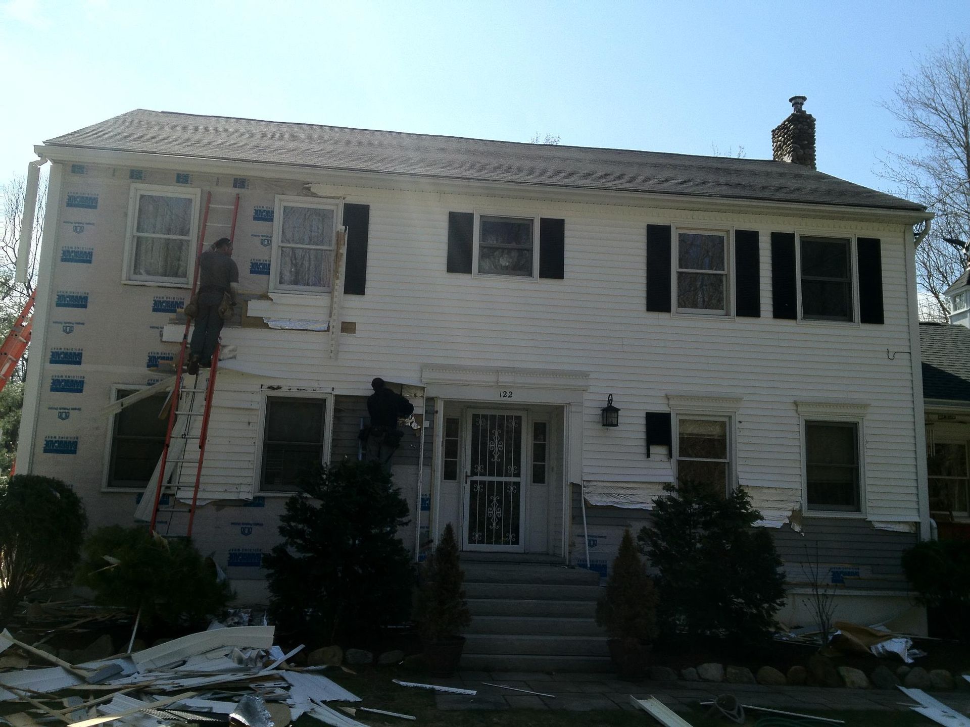 A white house with black shutters is being painted