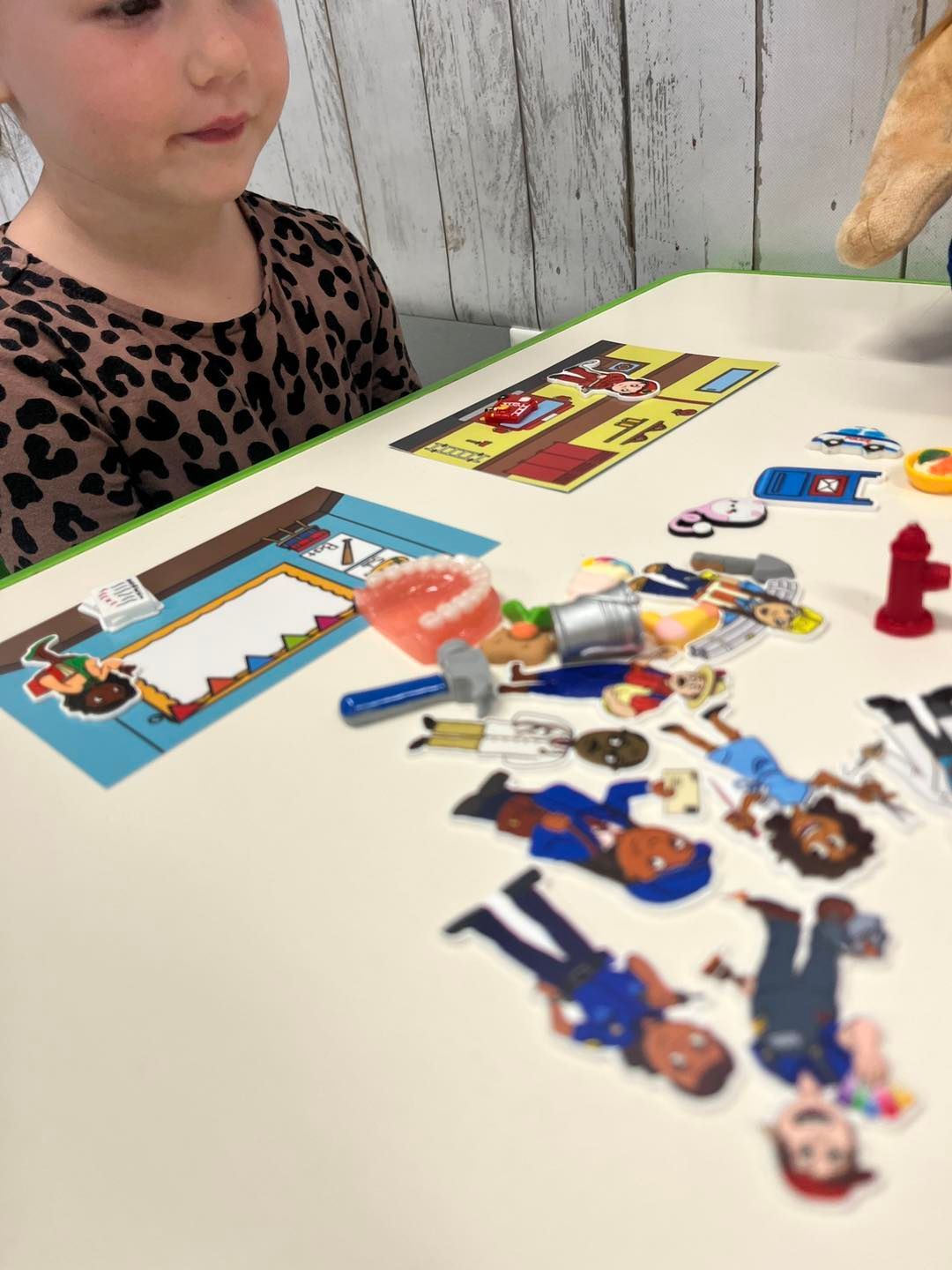 A little girl is sitting at a table with a bunch of stickers on it