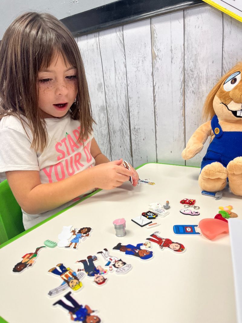 A little girl is sitting at a table with a stuffed animal.