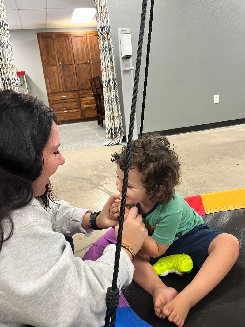 A woman is playing with a child on a swing.