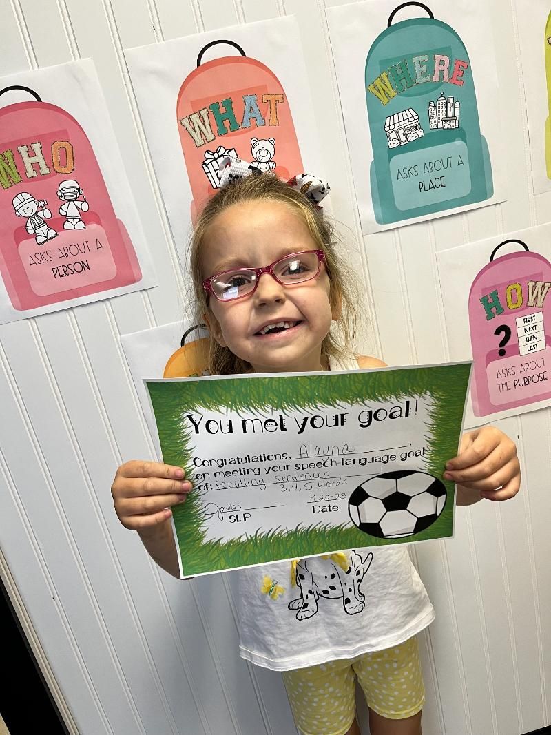 A little girl is holding a piece of paper that says `` year of your goal ''.