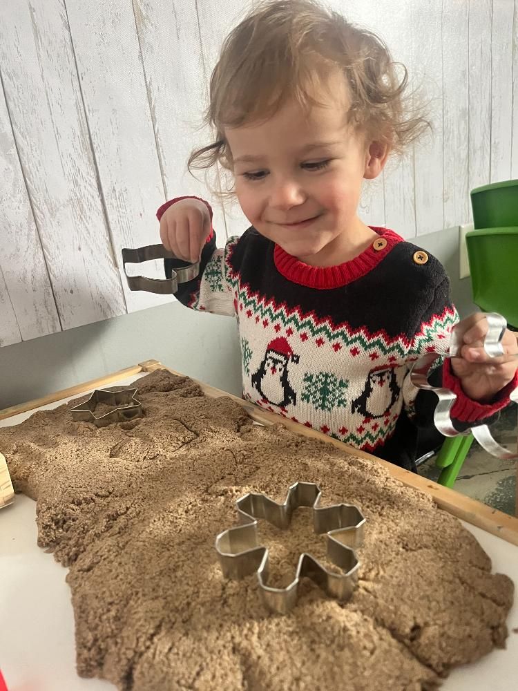 A little girl is playing with sand and a cookie cutter.