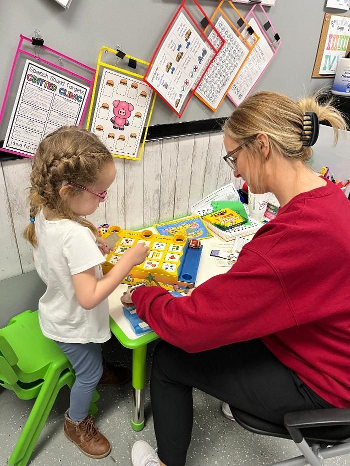 A woman is sitting at a table with a little girl.