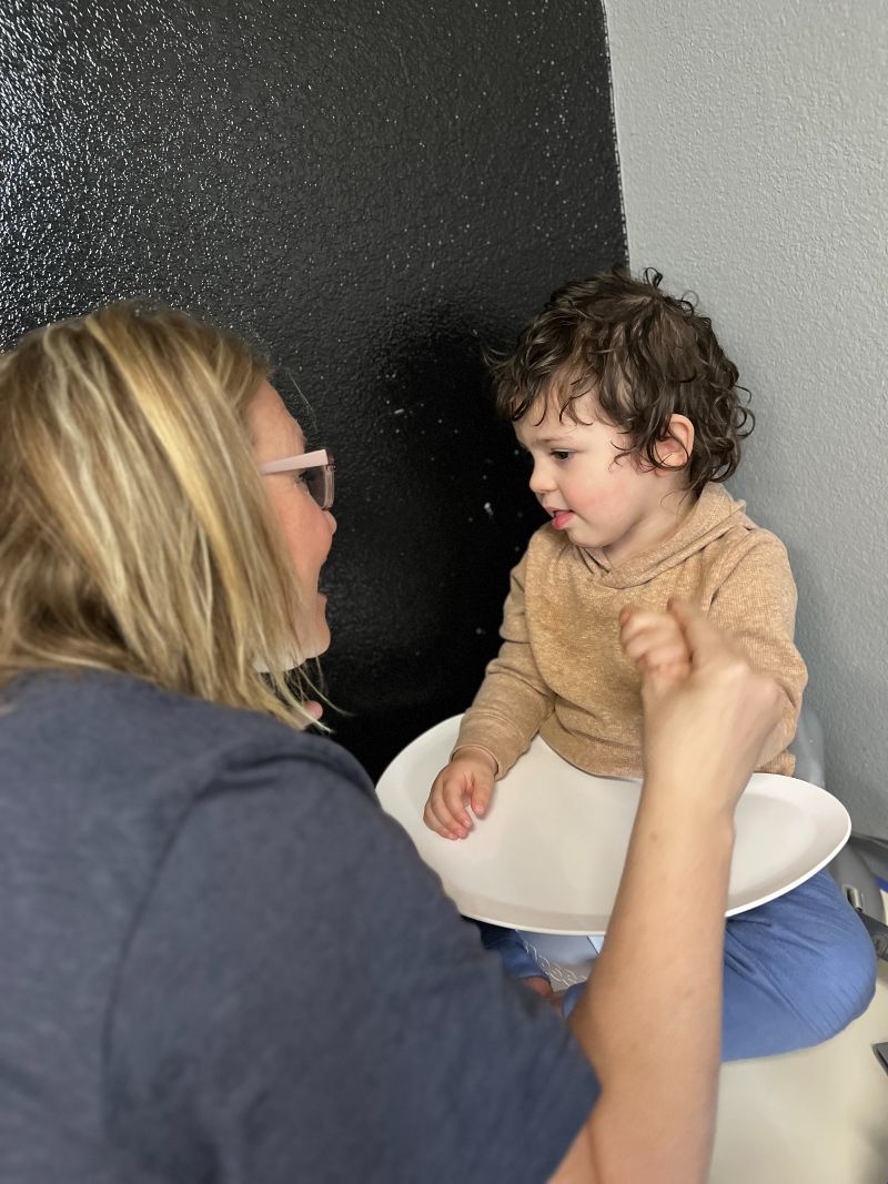 A woman is talking to a little boy who is sitting on a potty.