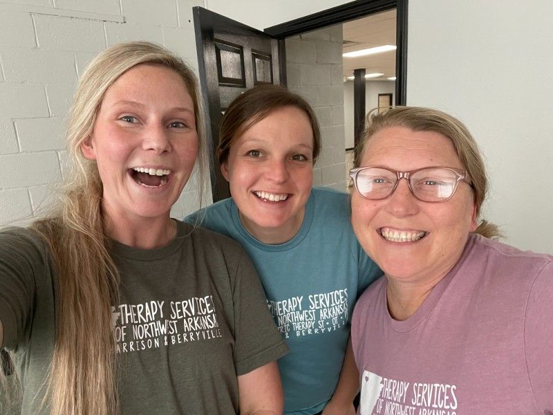 Three women are posing for a picture together and smiling.