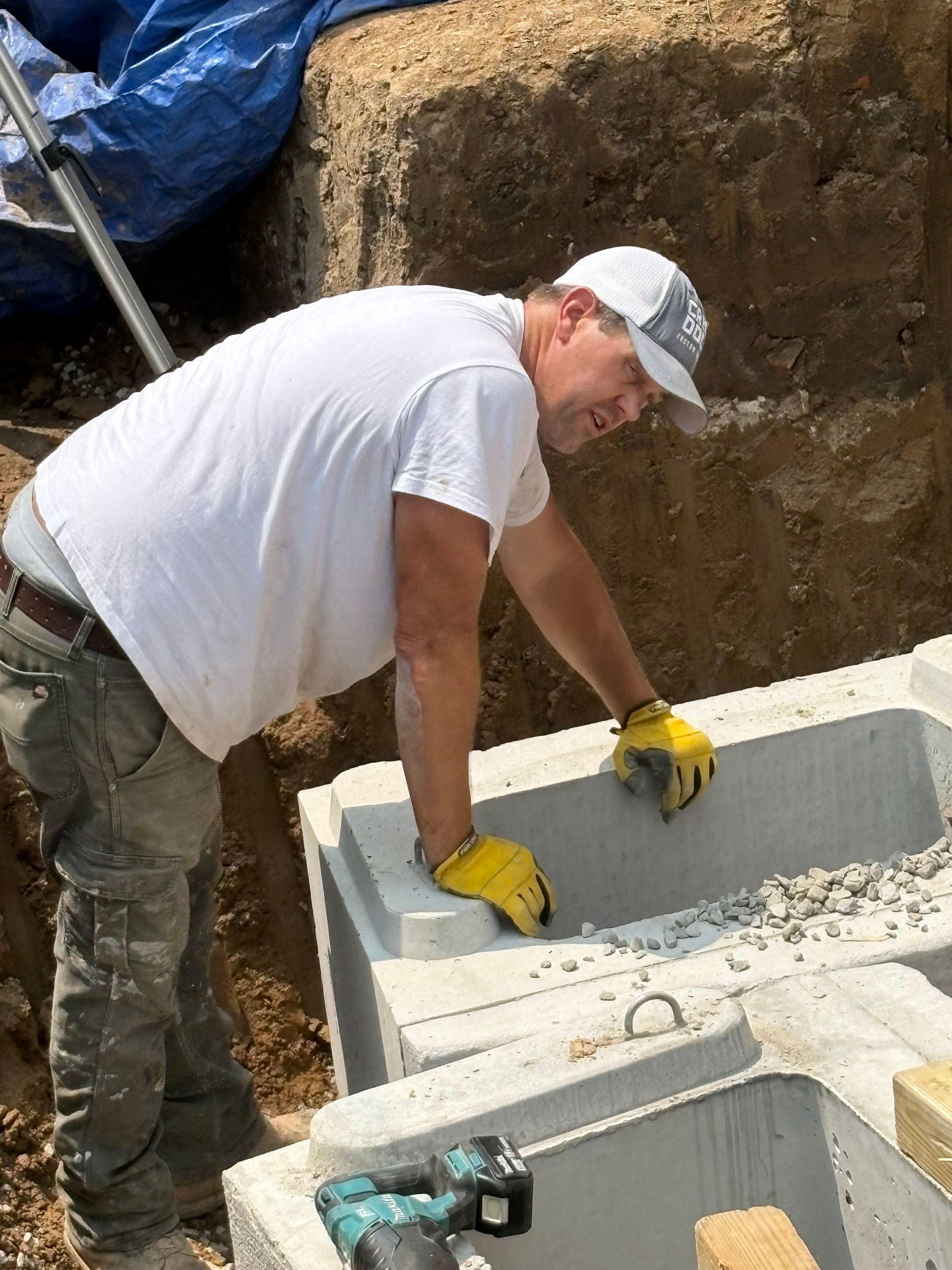 Worker in gloves installing concrete blocks at a construction site outdoors.