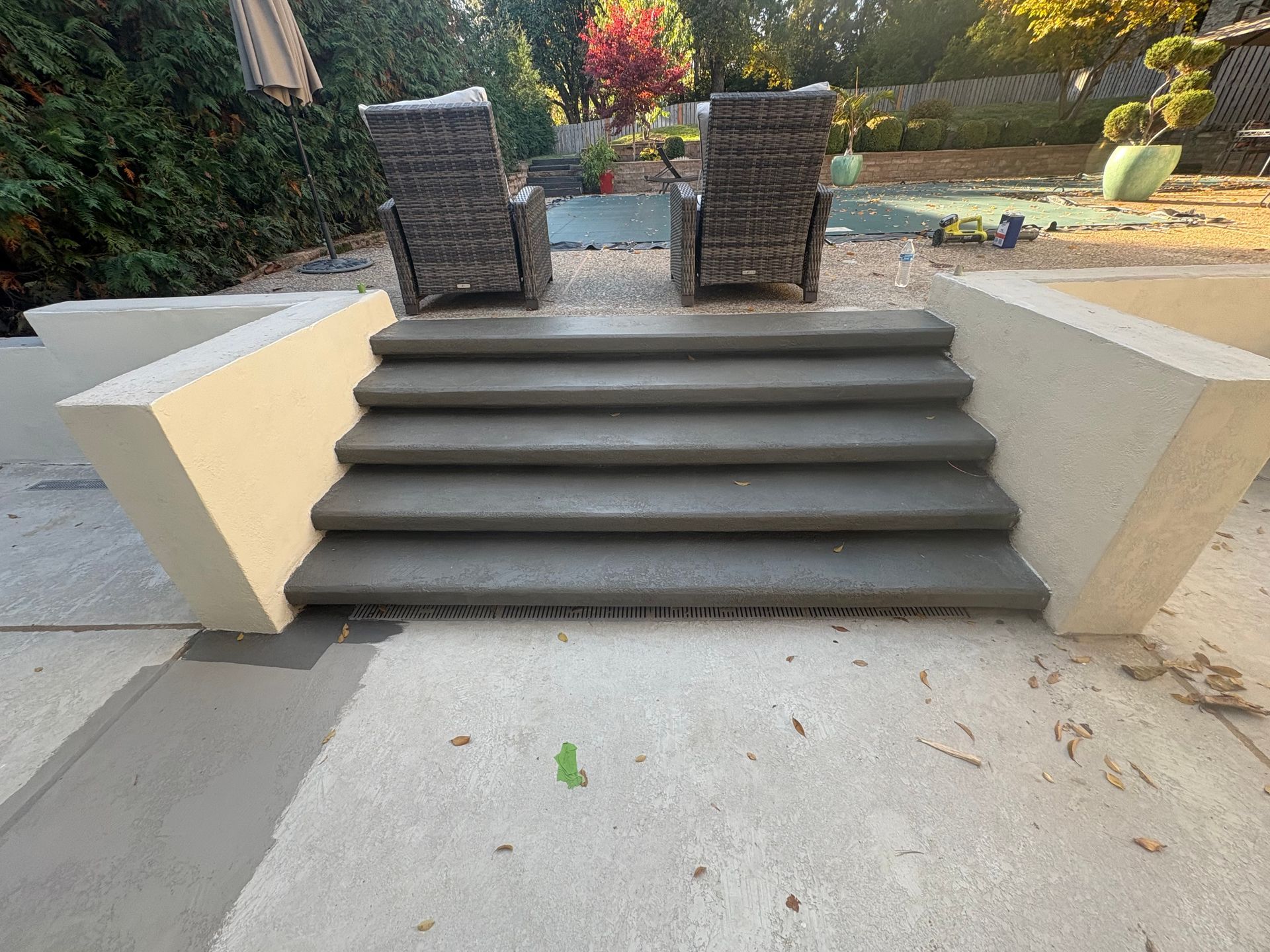 Patio steps leading to two woven chairs beside a landscaped garden.