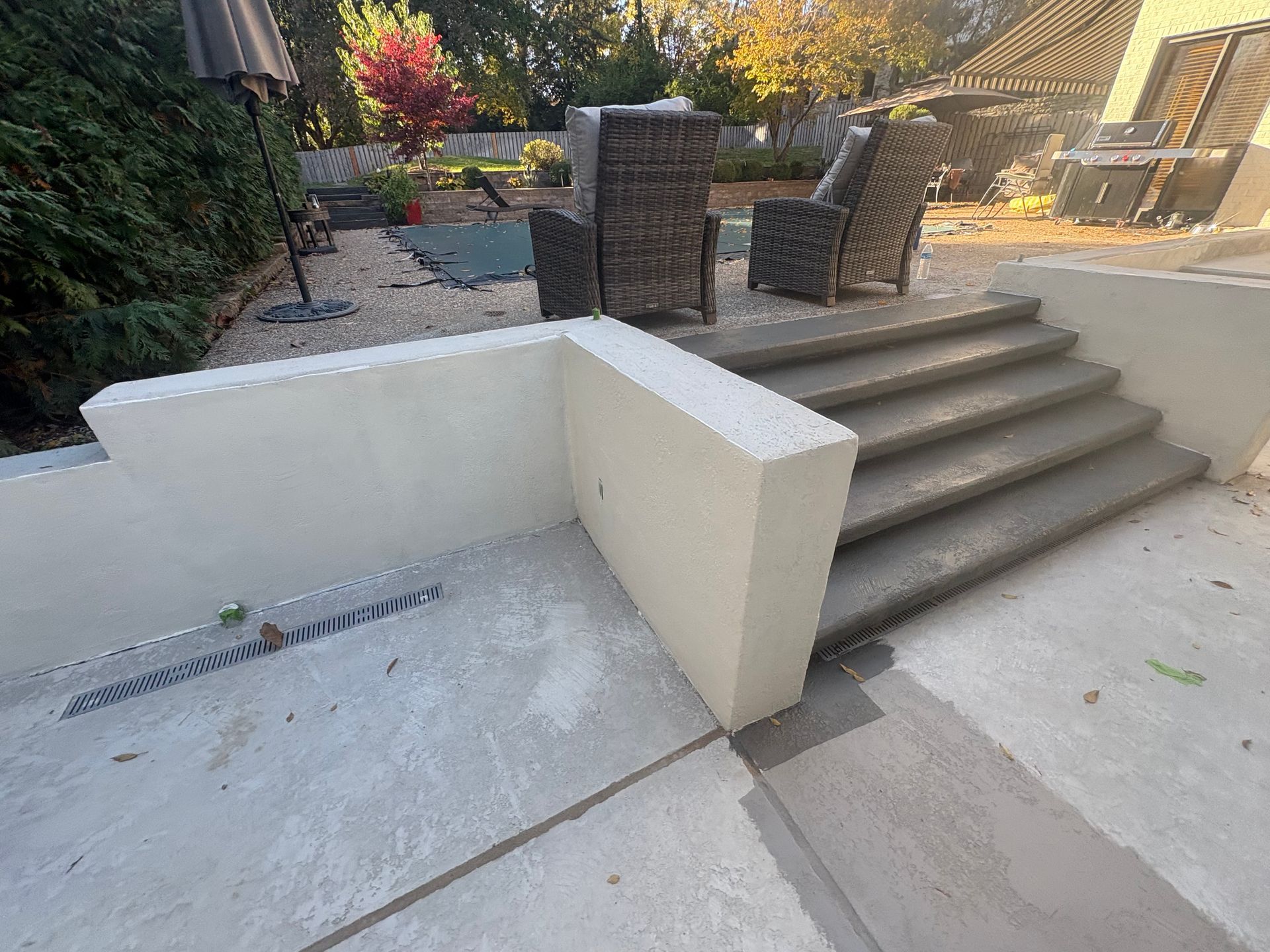 Patio steps beside a low white wall and brick seating area in a landscaped yard.