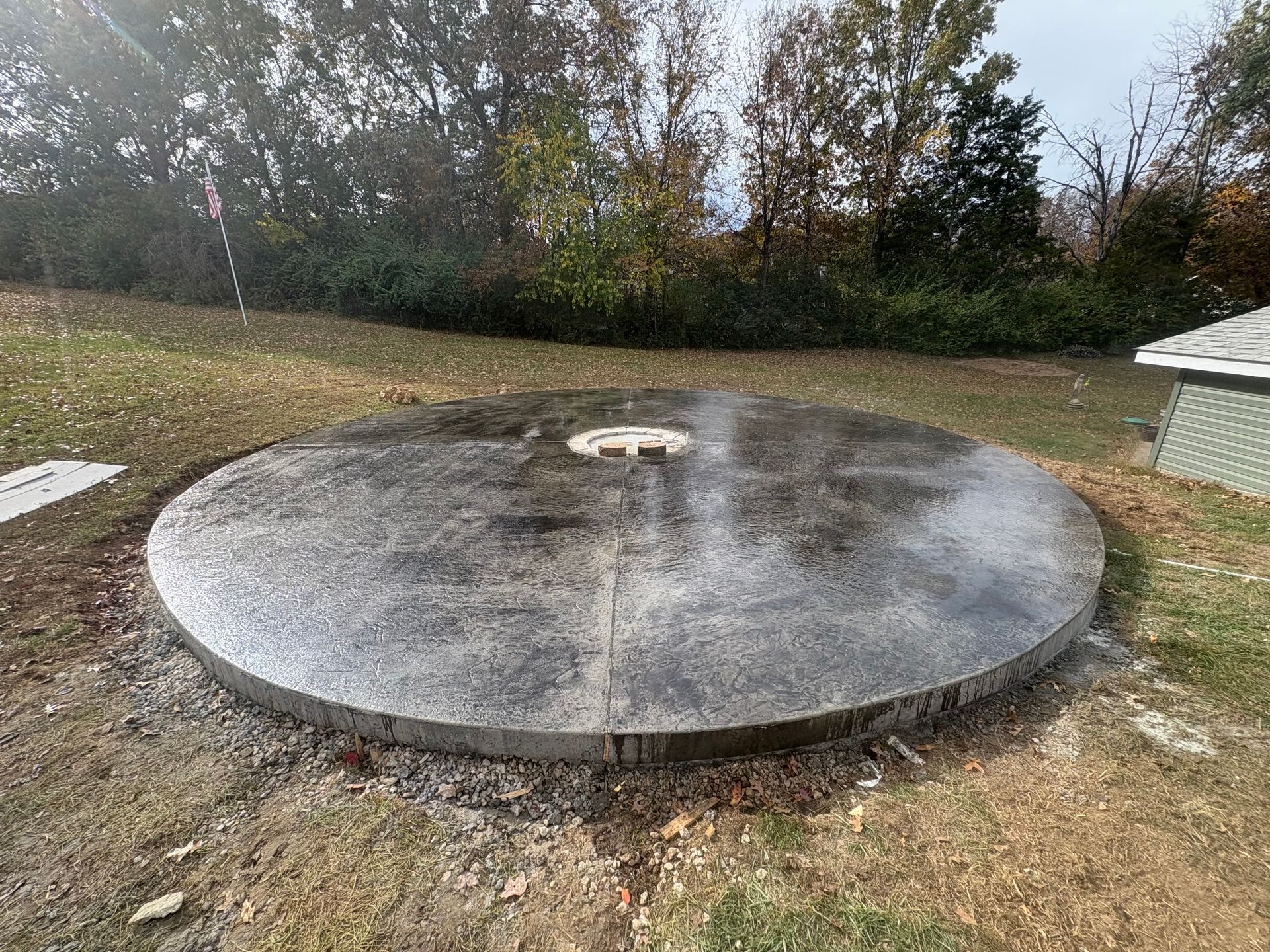 Concrete round platform in a grassy outdoor area with a small hole in the center.
