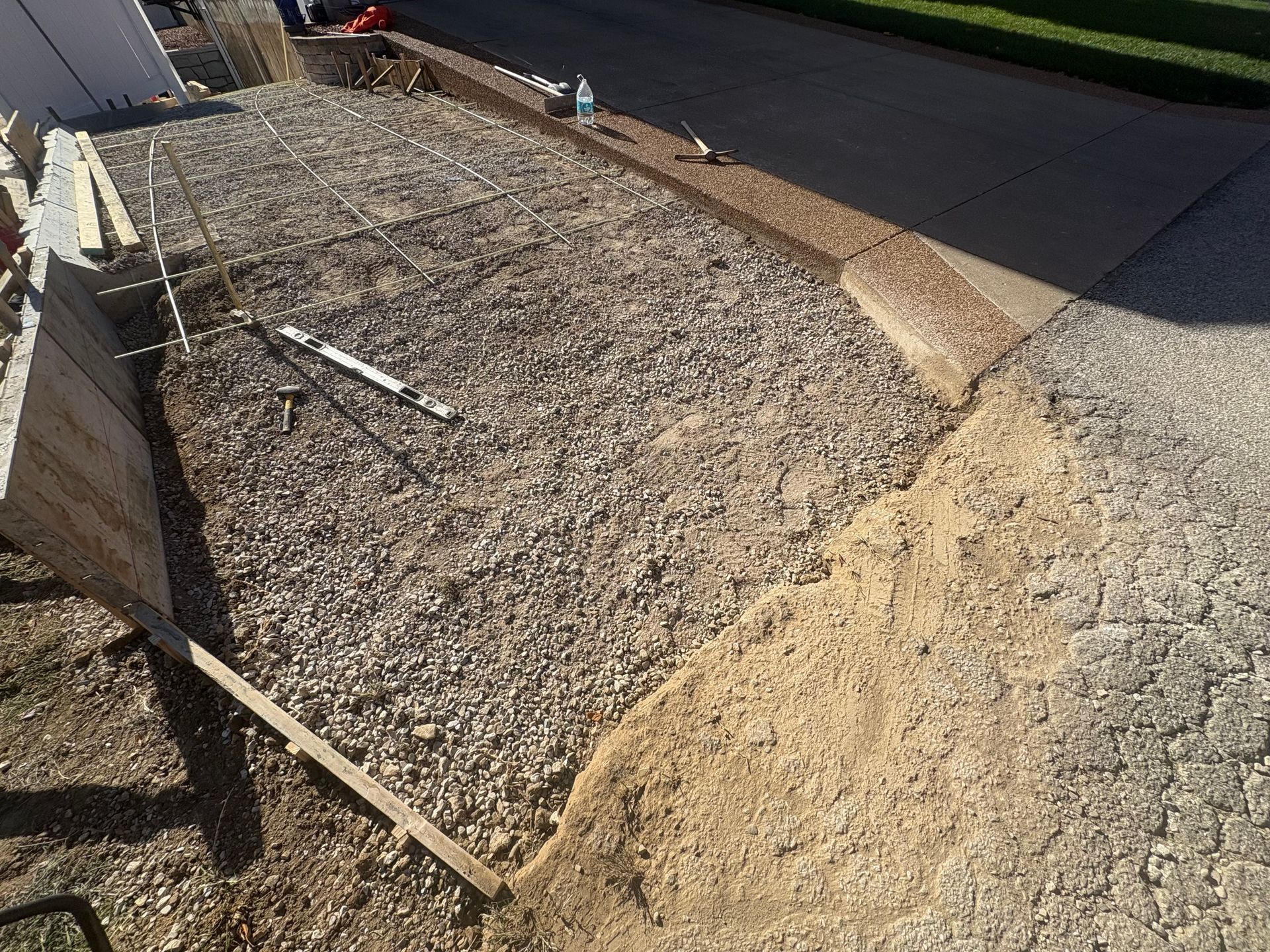 Gravel-covered walkway bordered by wooden edging and a sloped dirt path beside a road.
